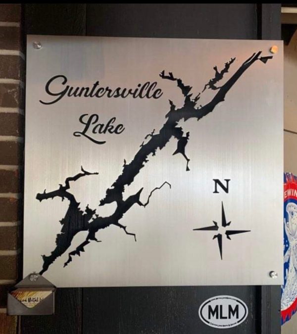 Guntersville Lake metal map with compass design, mounted on a brick wall.