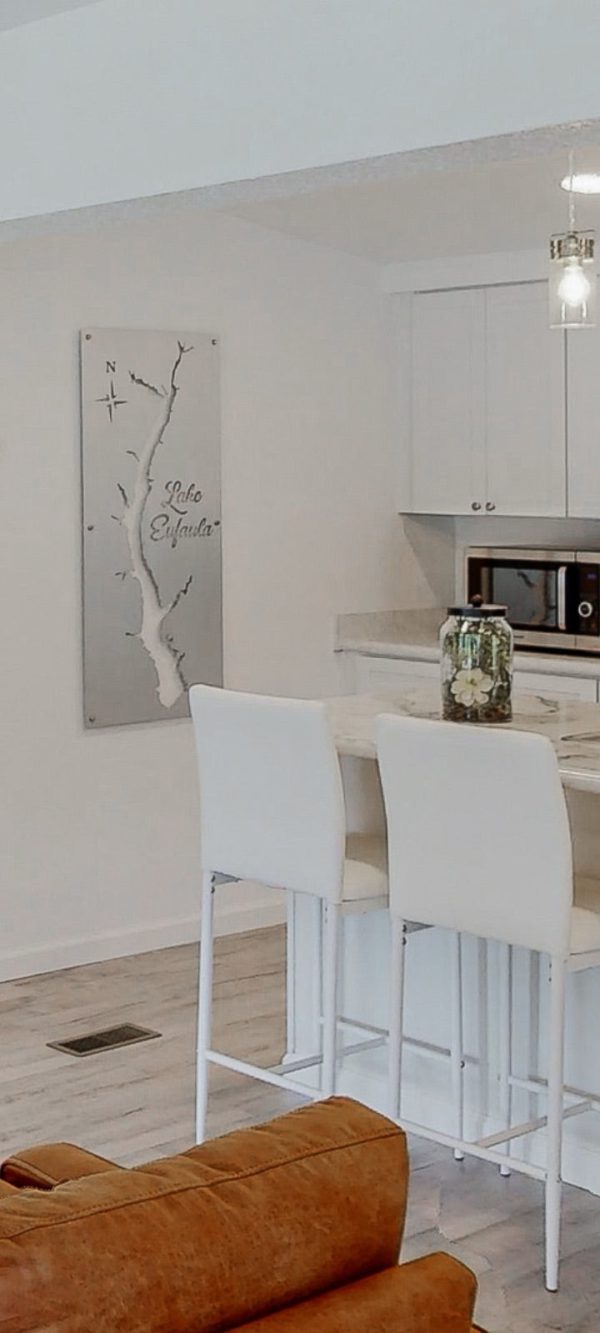 Lake Eufaula map on brushed metal, mounted in a modern kitchen with white decor and a floral centerpiece on the counter.