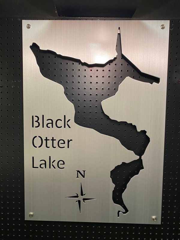 Black Otter Lake custom map sign with compass rose on perforated metal background.