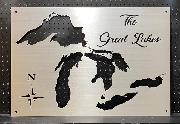 Great Lakes cutout map on brushed metal with "The Great Lakes" text and compass rose, mounted on a pegboard.