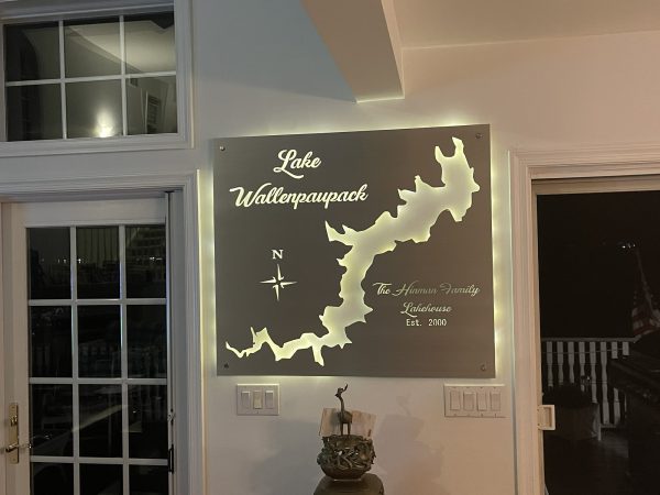 Metal map of Lake Wallenpaupack with compass and "The Hinman Family Lakehouse, Est. 2000," illuminated on a wall.